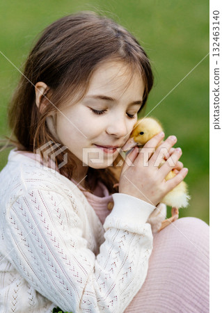 Young girl in garden playing with baby duckling. Young girl in garden playing with baby duckling. 132463140