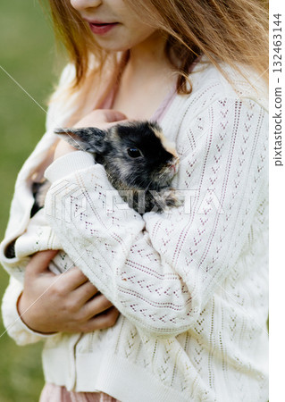 Young girl with pet rabbit sitting on grass. Young girl with pet rabbit sitting on grass. 132463144