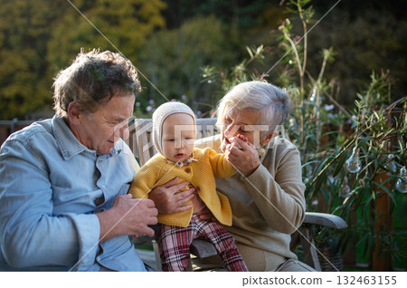 Grandparents holding baby in warm embrace during fall season. 132463155
