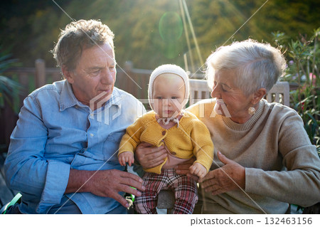 Grandparents holding baby in warm embrace during fall season. 132463156