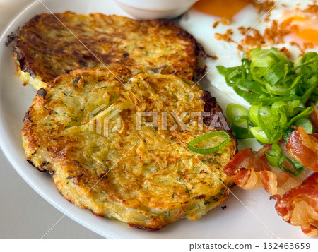 Potato pancakes with sour cream and onion on plate. Traditional meal, homemade flavor, and cozy rustic breakfast. 132463659