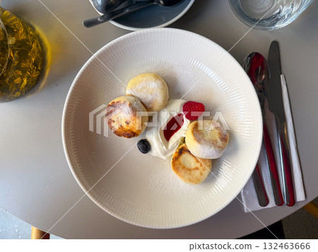 Cheesecakes with cream and berries on table top view. Sweet dessert, cozy breakfast and moment of comfort in cafe. Cheesecakes with cream and berries on table top view. Sweet dessert, cozy breakfast and moment of comfort in cafe. 132463666