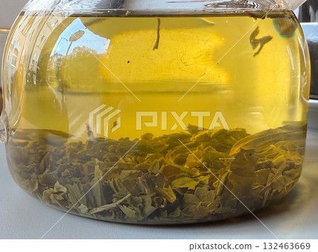Close-up of tea leaves brewing in glass teapot. Herbal infusion, natural texture, and detail of transparent warmth. 132463669