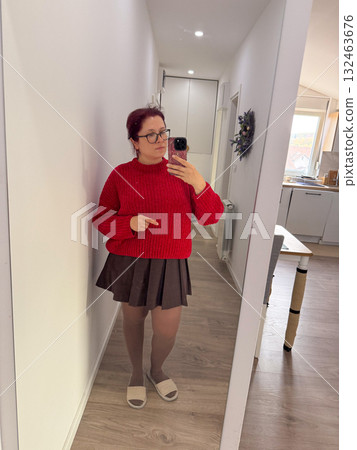 Woman in red knitted sweater and brown skirt taking mirror selfie. Bright accent, cozy mood, and daily outfit inspiration. Woman in red knitted sweater and brown skirt taking mirror selfie. Bright accent, cozy mood, and daily outfit inspiration. 132463676