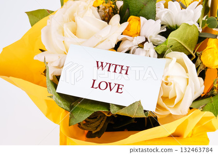 A vibrant arrangement of fresh flowers, including white roses and colorful blooms, is complemented by a note saying with love, conveying deep emotions and warmth 132463784