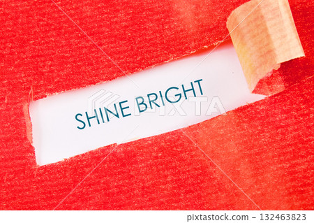 A bold red texture is torn open, revealing a bright white space with the words Shine Bright clearly displayed, offering a message of hope 132463823