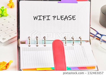 A notebook is open with a request for WiFi written clearly. Surrounding it are colorful sticky notes, a calculator, and a pair of glasses, highlighting a focused work environment A notebook is open with a request for WiFi written clearly. Surrounding it are colorful sticky notes, a calculator, and a pair of glasses, highlighting a focused work environment 132463857