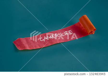 A vibrant red ribbon unfurls, featuring the inspiring words gamer life. Set against a calming blue backdrop, it captures the spirit of gaming culture and creativity A vibrant red ribbon unfurls, featuring the inspiring words gamer life. Set against a calming blue backdrop, it captures the spirit of gaming culture and creativity 132463943
