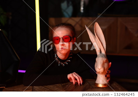 woman examines rabbit sculpture carefully, female investigator scrutinizes rabbit figure in dim woman examines rabbit sculpture carefully, female investigator scrutinizes rabbit figure in dim 132464245