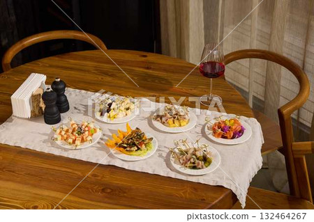 An elegant dining table setup with delicious dishes and exquisite wine beautifully arranged An elegant dining table setup with delicious dishes and exquisite wine beautifully arranged 132464267