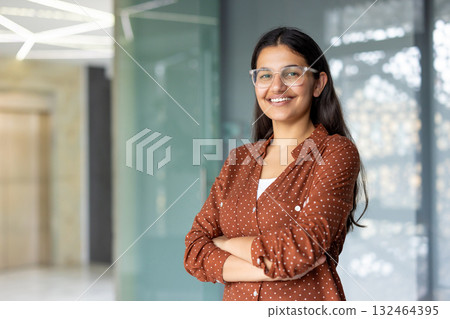 Successful confident businesswoman at workplace inside office, woman with crossed arms smiling and looking at camera, standing near window. Satisfied office worker of company Successful confident businesswoman at workplace inside office, woman with crossed arms smiling and looking at camera, standing near window. Satisfied office worker of company 132464395