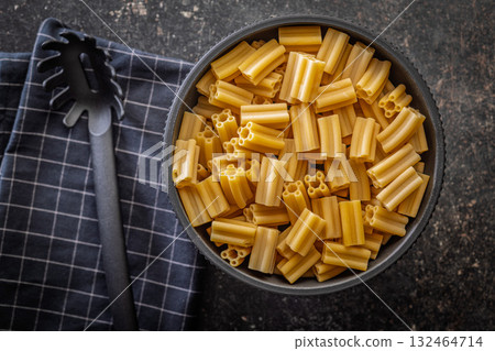 Cinque buchi. Uncooked italian pasta in bowl on black table. Top view. Cinque buchi. Uncooked italian pasta in bowl on black table. Top view. 132464714