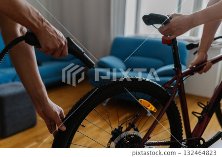Cropped shot of two cyclists cleaning bicycle wheel using high-pressure steam cleaner, removing stubborn dirt at home, demonstrating meticulous bicycle maintenance technique. Concept of bike service Cropped shot of two cyclists cleaning bicycle wheel using high-pressure steam cleaner, removing stubborn dirt at home, demonstrating meticulous bicycle maintenance technique. Concept of bike service 132464823