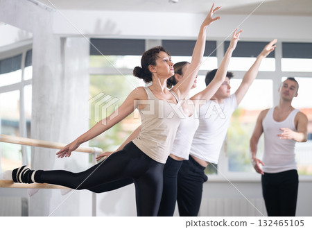 Young man trainer corrects dancers at barre Young man trainer corrects dancers at barre 132465105