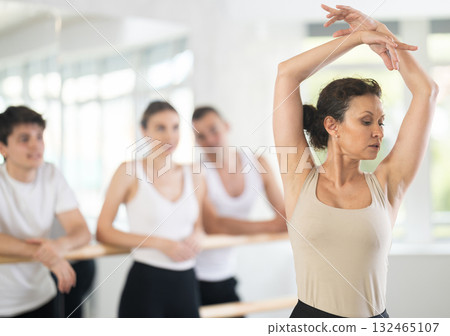 Pretty female choreographer conducting classes in ballet studio shows group correct performance of choreographic exercise Pretty female choreographer conducting classes in ballet studio shows group correct performance of choreographic exercise 132465107