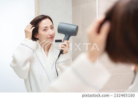 A woman using a hair dryer after taking a bath A woman using a hair dryer after taking a bath 132465180