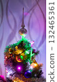 Decorated Christmas tree with colorful lights and ornaments, topped with a festive silver finial. Cozy holiday atmosphere with warm illumination and vibrant celebration mood 132465361