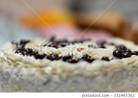 Close-up of a creamy dessert roll topped with chocolate chips. Delicious sweet pastry with soft texture and blurred colorful background, perfect for bakery, confectionery, or food photography Close-up of a creamy dessert roll topped with chocolate chips. Delicious sweet pastry with soft texture and blurred colorful background, perfect for bakery, confectionery, or food photography 132465362