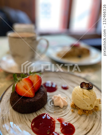 A delicious and beautifully plated gourmet dessert featuring a rich chocolate lava cake, or fondant, topped with fresh sliced strawberries A delicious and beautifully plated gourmet dessert featuring a rich chocolate lava cake, or fondant, topped with fresh sliced strawberries 132466316