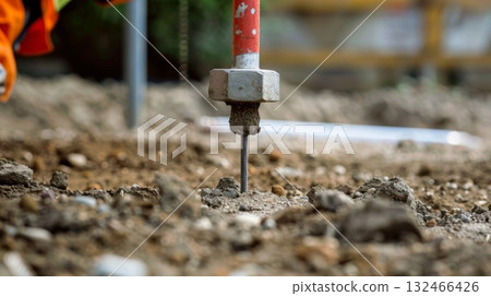 A closeup of a soil compaction test being conducted with a weight being dropped onto the ground to measure its compactness A closeup of a soil compaction test being conducted with a weight being dropped onto the ground to measure its compactness 132466426