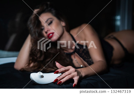 Woman in lace lingerie holding white clitoral vacuum stimulator. Woman in lace lingerie holding white clitoral vacuum stimulator. 132467319
