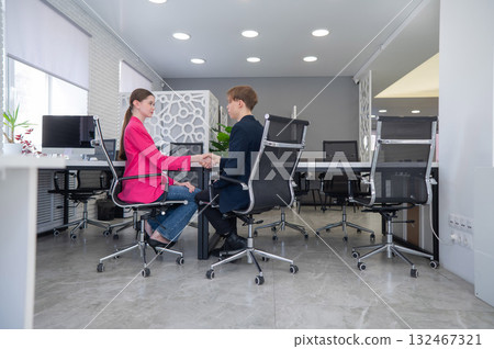 Man and woman shaking hands in office.  132467321