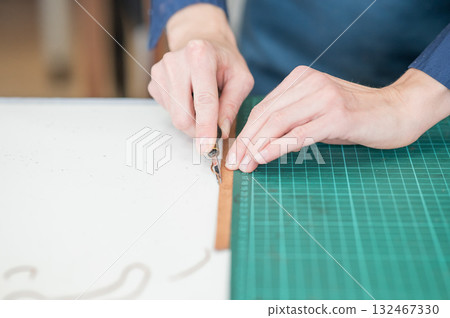 Leatherworker measuring and cutting leather in workshop. Leatherworker measuring and cutting leather in workshop. 132467330