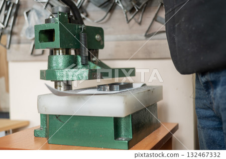 A tanner works with a press in his workshop. A tanner works with a press in his workshop. 132467332