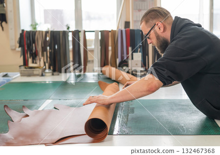 Caucasian bearded man working as a tanner in a workshop.  132467368