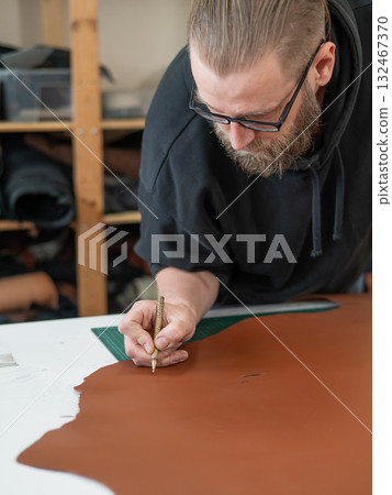 Caucasian bearded man working as a tanner in a workshop.  132467370