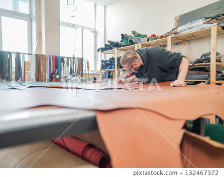 Caucasian bearded man working as a tanner in a workshop. Caucasian bearded man working as a tanner in a workshop. 132467372