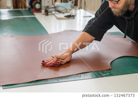 Caucasian bearded man working as a tanner in a workshop.  132467373