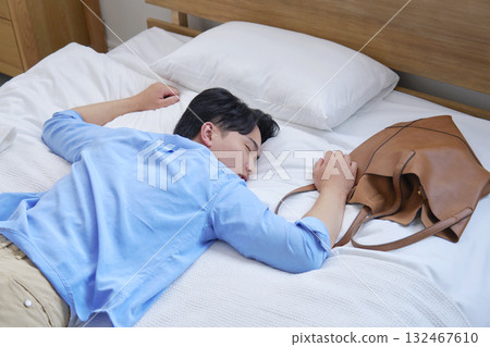 A tired man sleeping in bed in casual clothes A tired man sleeping in bed in casual clothes 132467610