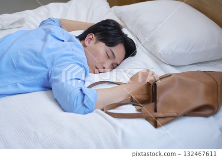 A tired man sleeping in bed in casual clothes A tired man sleeping in bed in casual clothes 132467611