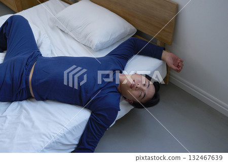 A man in his 20s sleeping in bed with a bad posture A man in his 20s sleeping in bed with a bad posture 132467639