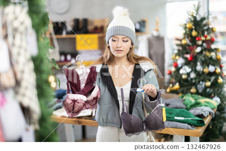 Woman in a winter hat choosing a bra set Woman in a winter hat choosing a bra set 132467926
