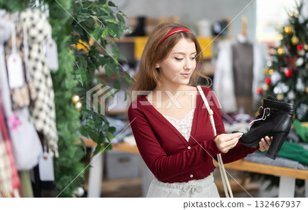Young woman choosing ankle boots on Christmas tree background Young woman choosing ankle boots on Christmas tree background 132467937