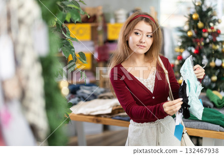 Young woman chooses panties in the store against the background of the Christmas tree Young woman chooses panties in the store against the background of the Christmas tree 132467938