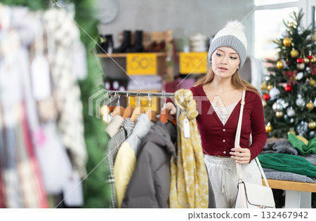 Young woman choosing coats and jackets at Christmas sale Young woman choosing coats and jackets at Christmas sale 132467942