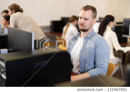 Portrait of concentrated man during lesson in computer room of school computer class Portrait of concentrated man during lesson in computer room of school computer class 132467991