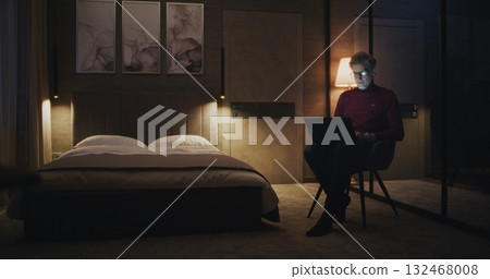 Stylish Mature Man Works on Laptop in Cozy Hotel Room at Night Stylish Mature Man Works on Laptop in Cozy Hotel Room at Night 132468008
