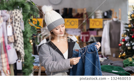 Woman in a knitted hat choosing jeans in a store 132468053