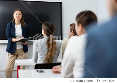 Knowledgeable female professor explaining subject to classroom full of students 132468106