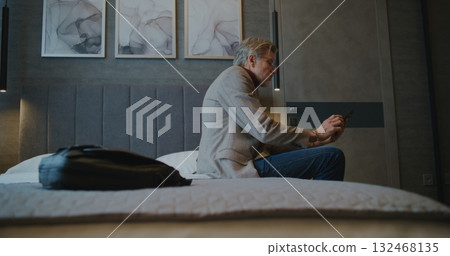 Fatigued Man Setting Down Bag Before Immediately Reaching For Smartphone Check Social Media 132468135