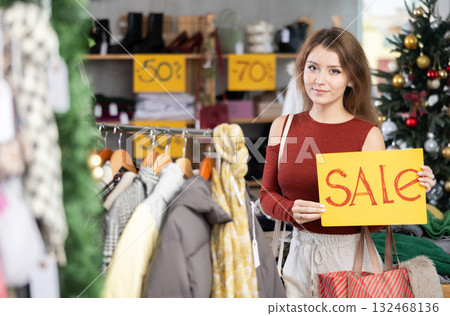 Girl with poster in hands announce mega Black Friday discounts in womens clothing store. Girl with poster in hands announce mega Black Friday discounts in womens clothing store. 132468136