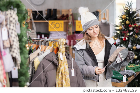 Young woman choosing winter hats on sale Young woman choosing winter hats on sale 132468159