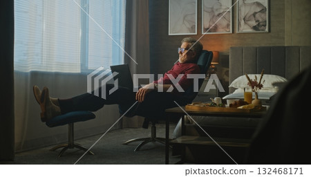Focused Senior Businessman Works on Laptop in Soft Morning Light of Hotel Room Focused Senior Businessman Works on Laptop in Soft Morning Light of Hotel Room 132468171