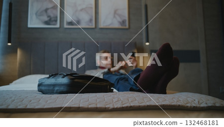 Mature Man in Hotel Room Scrolls Through News on Smartphone 132468181