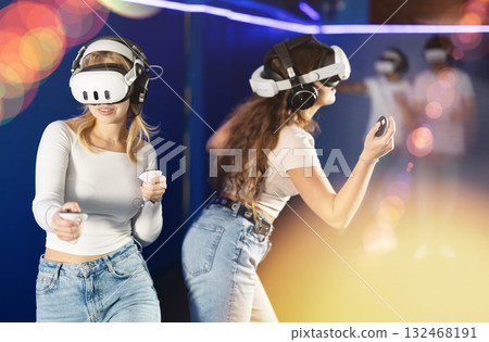 Two girls wearing virtual reality glasses participate in game with opponents 132468191