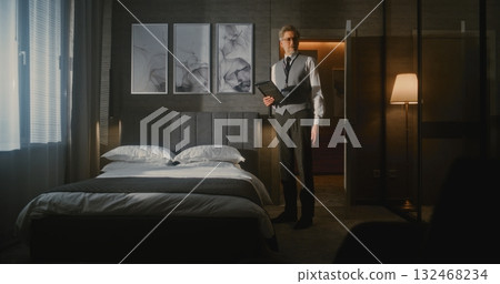 Mature Hotel Manager in Professional Business Attire Meticulously Checks and Photographs Bed 132468234
